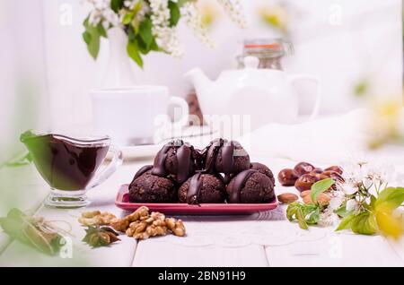 Palle energetiche con cioccolato su sfondo bianco di legno. Dieta di cibo crudo, veganismo. Tartufi sani di cioccolato a base di noci e datteri. Hea vegetariano Foto Stock