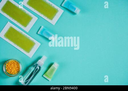 Prodotti depilazione su sfondo blu. Cera naturale di bellezza e altri cosmetici organici per marcare a caldo concetto mock-up. Vista dall'alto, spazio di copia. Foto Stock