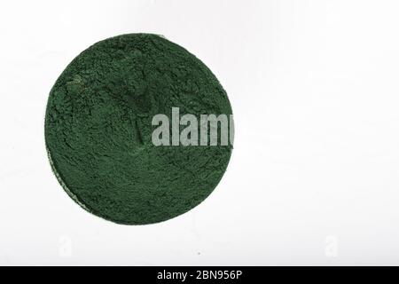 Un cucchiaio isolato di polvere di alghe di spirulina organica essiccata, su fondo bianco o rustico. Vita sana, ricette detox, frullato vegano crudo o ju Foto Stock