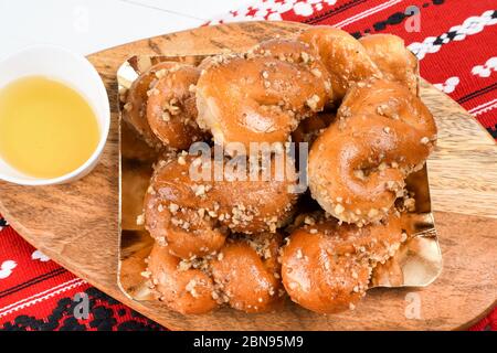 Concetto di cucina rumena. Mucenici fatti in casa, dolci tradizionali fatti nella figura 8 a sembrare ghirlande, cosparsi di miele e noci tritate. Foto Stock