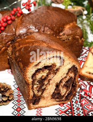 Primo piano di fette di pane tradizionale rumeno dolce fatto in casa chiamato 'cozonac', con cacao, uvetta, noci varie e patatine di cioccolato, pronto per essere mangiato Foto Stock
