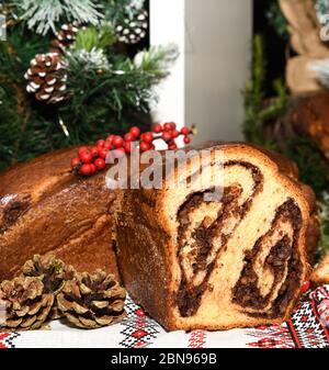 Primo piano di fette di pane tradizionale rumeno dolce fatto in casa chiamato 'cozonac', con cacao, uvetta, noci varie e patatine di cioccolato, pronto per essere mangiato Foto Stock