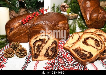 Primo piano di fette di pane tradizionale rumeno dolce fatto in casa chiamato 'cozonac', con cacao, uvetta, noci varie e patatine di cioccolato, pronto per essere mangiato Foto Stock