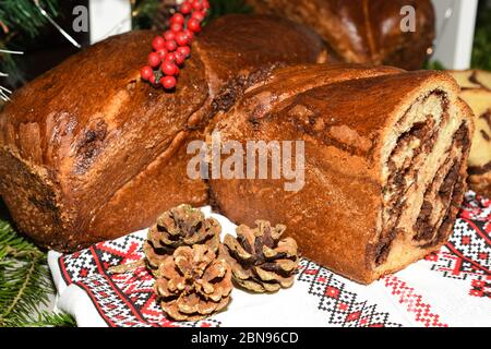 Primo piano di fette di pane tradizionale rumeno dolce fatto in casa chiamato 'cozonac', con cacao, uvetta, noci varie e patatine di cioccolato, pronto per essere mangiato Foto Stock