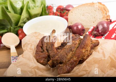 Succulente e fresco costolette di maiale rumene tradizionale o 'cicica de porca', grigliate e cotte al forno, su carta da forno insalata di verdure e purea di patate Foto Stock