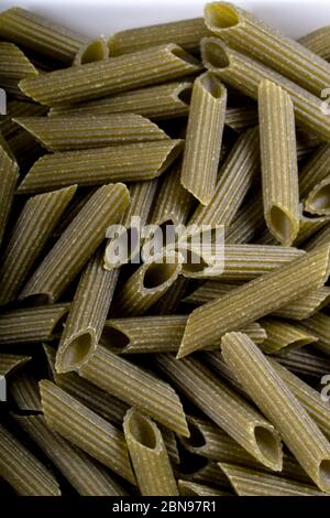 Pasta di penne senza glutine di piselli verdi su tagliere di legno. Basilico, pomodori e aglio. Shot dall'alto e closeup.food background penne italiano Foto Stock