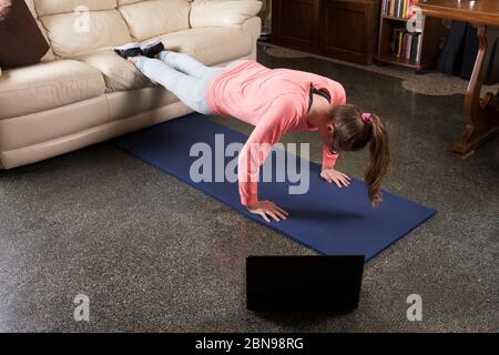 La ragazza sta facendo pressione sul coch nella stanza a casa. Allenamento fitness femminile per rimanere in forma e in salute. Self care a casa e allenamenti a casa, nuovo Foto Stock