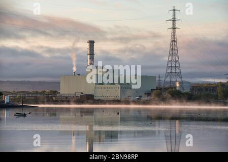 Derry, UK - 26 aprile 2020: Stazione elettrica di Coolkeerah ESB, mentre la nebbia sale dalle acque del fiume Foyle vicino a Derry, Irlanda del Nord Foto Stock