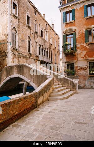 Un bel ponte in pietra con una scalinata sul canale veneziano sulle strade di Venezia, in Italia. Le facciate di splendidi edifici in mattoni con Foto Stock