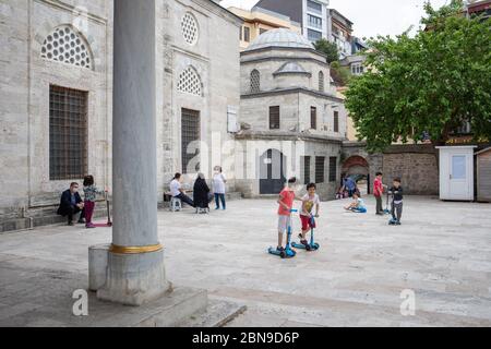 I bambini hanno preso aria fresca e hanno giocato a giocare con le loro famiglie nel cortile della Moschea del Sultano di Mihrimah. Foto Stock