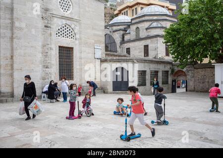 I bambini hanno preso aria fresca e hanno giocato a giocare con le loro famiglie nel cortile della Moschea del Sultano di Mihrimah. Foto Stock