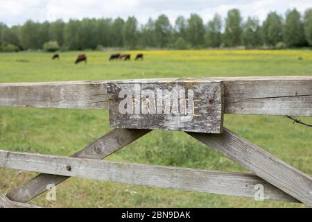 Cartello privato su cancello di legno di fronte al verde campo rurale Foto Stock