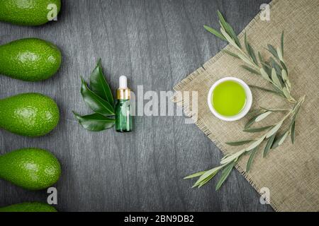 Olio cosmetico di avocado in bottiglia contagocce, mock up. Bottiglia di vetro. Avocado e olio d'oliva mock up. Cosmetici naturali eco-cura della pelle. Olio essenziale di avocado Foto Stock