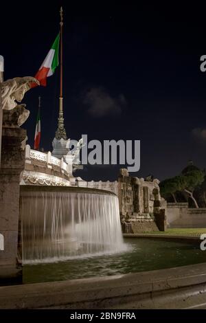 Roma, Italia: L'altare della fontana della Patria di Roma di notte con la bandiera italiana che sorvola Foto Stock