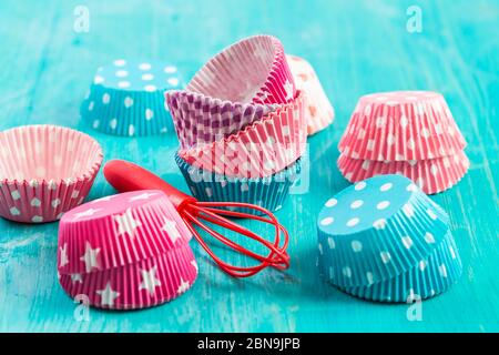 Variazione di forme di carta piccola per cuocere cupcake e muffin con wisp. Rivestimenti in carta colorati. Foto Stock