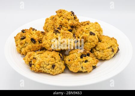 Un mucchio di dolci tradizionali freschi di roccia dorata cotta in casa con ribes presentati su un piatto bianco cinese con sfondo bianco Foto Stock