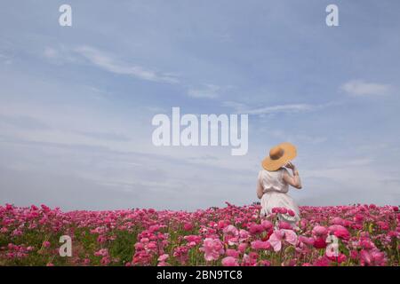 Donna che indossa cappello di paglia in fiori rosa Foto Stock
