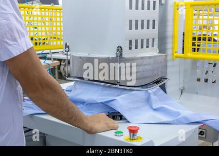 Macchine automatiche per stirare Knitwear e camicia con pressa nella fabbrica tessile. Foto Stock