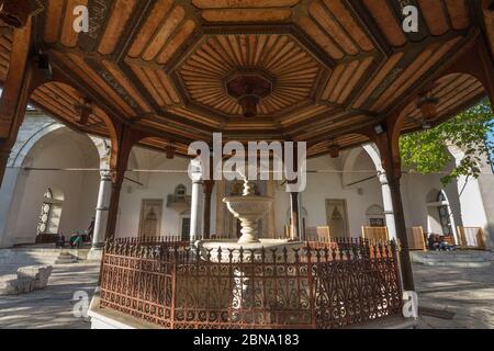 SARAJEVO, BOSNIA - 17 APRILE 2017: Fontana della Moschea Gazi Husrev begova con le persone che pregano sullo sfondo. La moschea è uno dei punti di riferimento principali Foto Stock