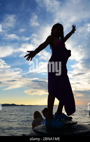 Una ragazza che salta nel mare Adriatico dalla passeggiata a Zara, Croazia. Foto Stock