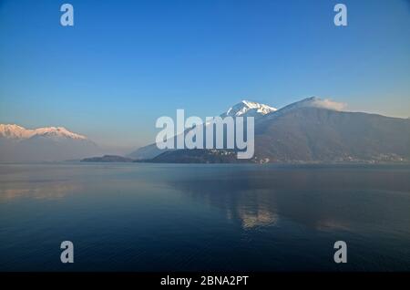 Immagine ipnotizzante delle montagne innevate che si riflettono sull'acqua sottostante il cielo azzurro Foto Stock