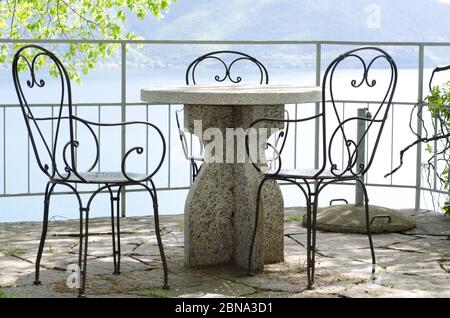 Patio con tavolo in pietra e sedie con vista sopra un lago Foto Stock