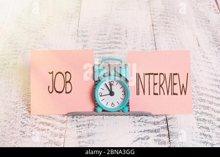 Nota di scrittura che mostra Intervista lavoro. Concetto di business per la valutazione Domande risposte assunzione pannello occupazione Mini orologio blu sveglia in piedi sopra buf Foto Stock