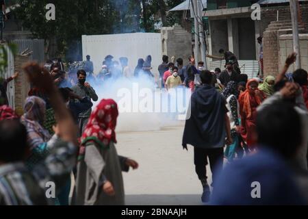 Gli abitanti del villaggio di Kashmiri corrono per la copertura mentre una conchiglia di gas lacrimogeni sparata da uomini di polizia indiani esplode vicino a loro durante una protesta contro l'uccisione di un civile nel villaggio di Makhama, ad ovest di Srinagar, Kashmir controllato dall'indiano, mercoledì 13 maggio 2020. Mercoledì, soldati indiani hanno ucciso con morte il giovane ad un checkpoint nella regione himalayana del Kashmir, hanno detto residenti e funzionari, scatenando proteste contro l'India e scontri nella regione contesa. La polizia della riserva centrale dell'India ha detto che l'uomo stava guidando un'automobile ed ha ignorato i segnali per arrestarsi a due punti di controllo nella periferia occidentale di Srinagar, il Foto Stock