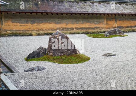 La vista di gruppi separati di massi circondati dalle onde di ghiaia bianca nel famoso giardino di pietra Zen del tempio Ryoan-ji. Kyoto. Giappone Foto Stock