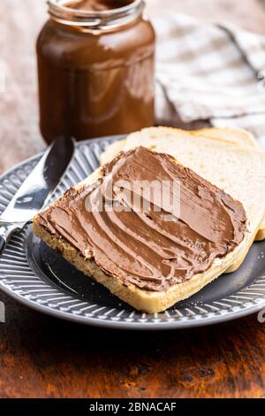 Tostare il pane con la nocciola spalmata. Crema di cioccolato dolce sul piatto. Foto Stock