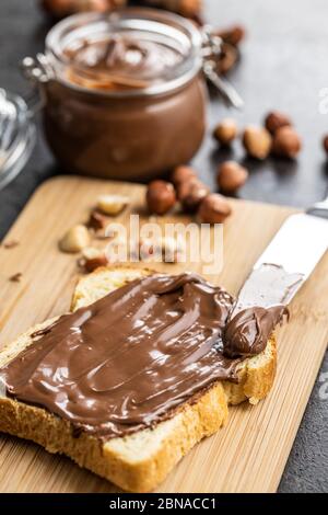 Tostare il pane con la nocciola spalmata. Crema di cioccolato dolce sul tagliere. Foto Stock