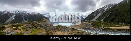 Ponte sospeso sul fiume Hooker, dietro il lago Hooker e il monte Cook, il parco nazionale Mount Cook, le Alpi meridionali, Hooker Valley, Canterbury Region, sud Foto Stock