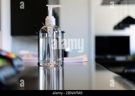 Bottiglia di igienizzatore per mani sul banco della reception dell'ufficio per aiutare a pulire le mani Foto Stock