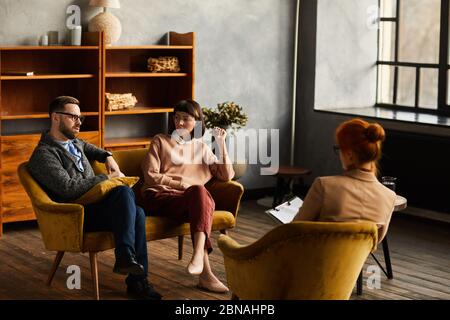 Gruppo di persone che lavorano seduti su poltrone e discutono insieme i progetti futuri durante una riunione in ufficio Foto Stock