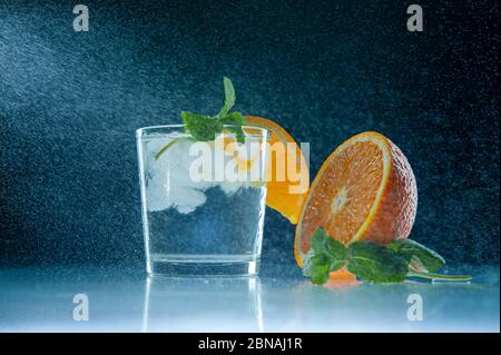 Cocktail con ghiaccio e arancio su sfondo scuro con spruzzi d'acqua Foto Stock