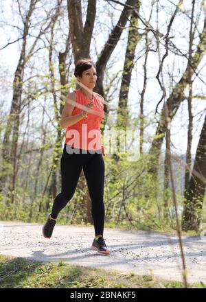 Donna, 40-45 anni, jogging in una zona forestale a Monaco, Baviera, Germania. Foto Stock