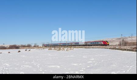 Treni Virgin Bombardier classe 221 diesel super voyager treno 221106 che passa Shap pozzi sulla linea principale elettrificata della costa occidentale nella neve invernale Foto Stock