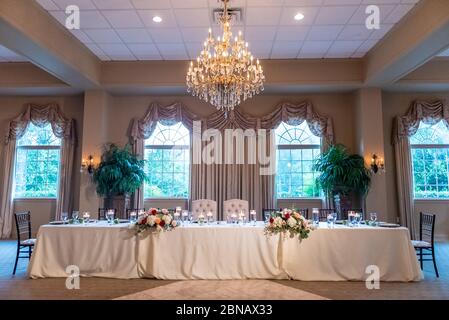 Elegante tavolo nella sala per matrimoni con un bellissimo lampadario Foto Stock