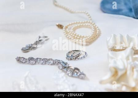 Primo piano di preziosi accessori con anelli diamantati e braccialetto e una collana di perle Foto Stock