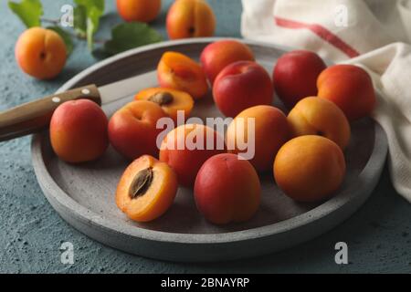 Composizione con vassoio di albicocche su fondo cementizio Foto Stock