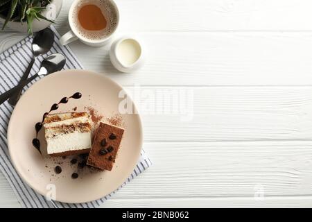 Composizione con gustoso tiramisù e bevanda al cacao su tavolo di legno bianco. Delizioso dessert Foto Stock