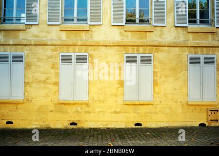 Antico edificio giallo con persiane chiuse sul primo piano e aperto al secondo. Foto Stock