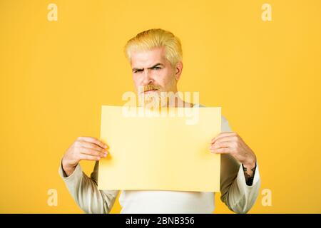 Il giovane mostra un foglio di carta nella fotocamera su uno sfondo a colori. Spazio di copia Foto Stock