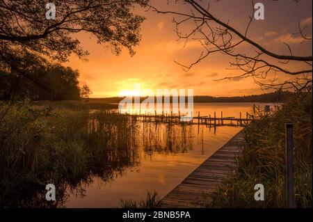 Ahrensberg, Germania. 09 aprile 2016. Un molo presso un lago di Meclemburgo, sullo sfondo il sole che sorge. Il Distretto dei Laghi di Mecklenburg è una meta turistica molto apprezzata, soprattutto in primavera e in estate molti turisti cercano pace e relax. Credit: Ingolf König-Jablonski/dpa-Zentralbild/ZB/dpa/Alamy Live News Foto Stock