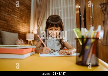 felice bambino asiatico che studia a casa la sera Foto Stock