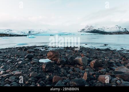 Ghiacciaio mozzafiato in Islanda con roccia nera e grandi ghiacci, sciogliendo il ghiaccio a causa del cambiamento climatico Foto Stock