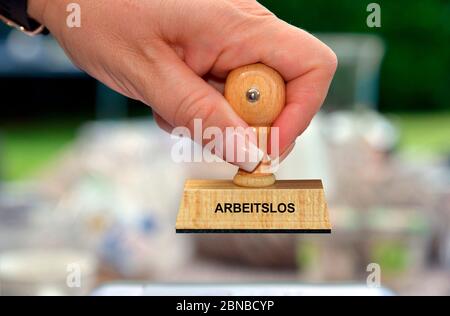 Timbro in mano di una donna che scritta Arbeitslos, Germania Foto Stock