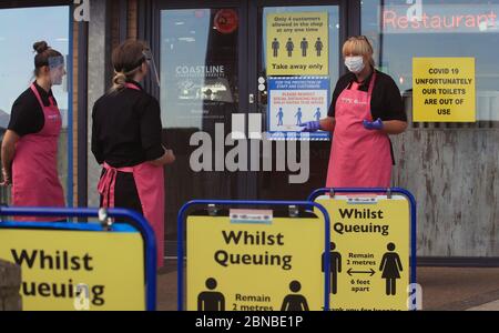 Il personale del negozio di pesce e patatine e della gelateria sulla spiaggia di Blyth, Northumberland, indossa i dispositivi di protezione individuale (PPE) mentre mettono i cartelli di allontanamento sociale per i clienti. Il ristorante ha riaperto per ordini di take away dopo l'allentamento delle restrizioni di blocco durante la pandemia del coronavirus. Foto Stock