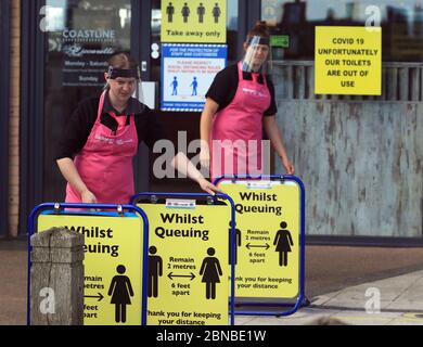 Il personale del negozio di pesce e patatine e della gelateria sulla spiaggia di Blyth, Northumberland, indossa i dispositivi di protezione individuale (PPE) mentre mettono i cartelli di allontanamento sociale per i clienti. Il ristorante ha riaperto per ordini di take away dopo l'allentamento delle restrizioni di blocco durante la pandemia del coronavirus. Foto Stock