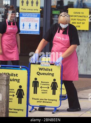 Il personale del negozio di pesce e patatine e della gelateria sulla spiaggia di Blyth, Northumberland, indossa i dispositivi di protezione individuale (PPE) mentre mettono i cartelli di allontanamento sociale per i clienti. Il ristorante ha riaperto per ordini di take away dopo l'allentamento delle restrizioni di blocco durante la pandemia del coronavirus. Foto Stock